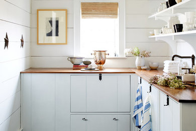 Kitchen - cottage l-shaped gray floor kitchen idea in New York with flat-panel cabinets, white cabinets, wood countertops and no island
