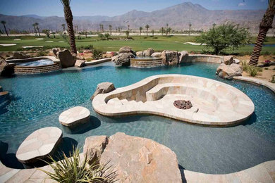 Photo of a large traditional backyard custom-shaped natural pool in Los Angeles with a water feature and concrete pavers.