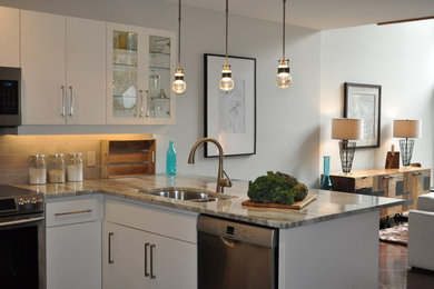 Example of a small transitional u-shaped open concept kitchen design in Toronto with a double-bowl sink, flat-panel cabinets, white cabinets, marble countertops, beige backsplash, stone tile backsplash and stainless steel appliances