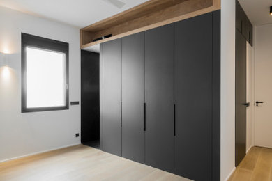 Modelo de dormitorio principal y gris y blanco minimalista grande con paredes blancas, suelo de madera en tonos medios y suelo marrón