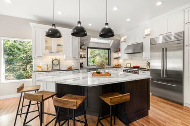 Example of a mid-sized country medium tone wood floor eat-in kitchen design in Seattle with an island, an undermount sink, shaker cabinets, white backsplash, ceramic backsplash and stainless steel appliances