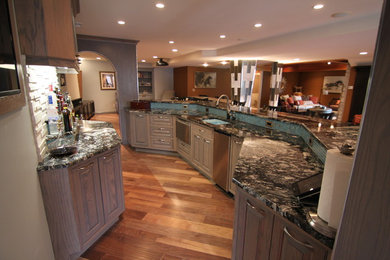 Seated home bar - huge transitional galley dark wood floor and brown floor seated home bar idea in Miami with an undermount sink, raised-panel cabinets, gray cabinets, granite countertops and white backsplash