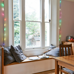 Cette image montre une salle à manger ouverte sur le salon traditionnelle de taille moyenne avec un sol en bois brun et un mur rose.