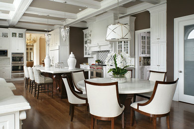 Example of a huge classic u-shaped dark wood floor eat-in kitchen design in New York with a farmhouse sink, raised-panel cabinets, white cabinets, marble countertops, white backsplash, stone tile backsplash, paneled appliances and an island