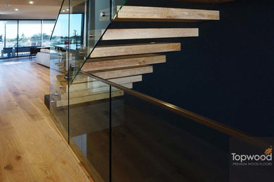 Photo of a modern wood floating staircase in Perth with glass railing.