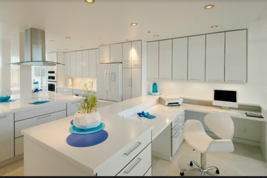Inspiration for a large modern galley travertine floor and beige floor open concept kitchen remodel in Vancouver with an undermount sink, flat-panel cabinets, white cabinets, solid surface countertops, white backsplash, stone slab backsplash, white appliances, an island and white countertops