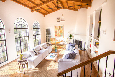 Example of a large tuscan open concept light wood floor living room design in Los Angeles with white walls, a corner fireplace, a plaster fireplace and no tv
