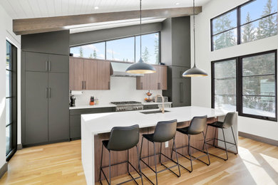 Example of a large trendy single-wall exposed beam open concept kitchen design in Denver with an undermount sink, flat-panel cabinets, black cabinets, quartz countertops, white backsplash, quartz backsplash, stainless steel appliances, an island and white countertops