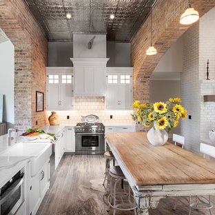 Mittelgroße Shabby-Style Küche in L-Form mit Vorratsschrank, Landhausspüle, Schrankfronten im Shaker-Stil, weißen Schränken, Quarzwerkstein-Arbeitsplatte, Küchenrückwand in Beige, Rückwand aus Mosaikfliesen, Küchengeräten aus Edelstahl, Keramikboden, Kücheninsel und grauem Boden in Detroit