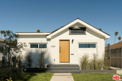 Example of a mid-sized white one-story exterior home design in Los Angeles with a black roof