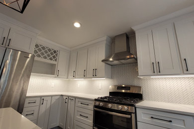 Kitchen - mid-sized u-shaped kitchen idea in Detroit with an undermount sink, shaker cabinets, white cabinets, quartz countertops, white backsplash, porcelain backsplash, stainless steel appliances, an island and multicolored countertops