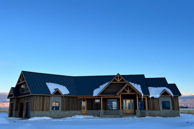 Inspiration for a large timeless brown two-story wood and board and batten exterior home remodel in Other with a metal roof and a black roof