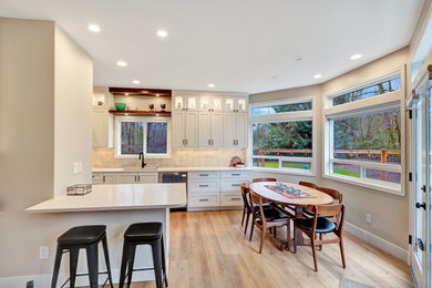Eat-in kitchen - mid-sized l-shaped eat-in kitchen idea in Seattle with shaker cabinets, white cabinets, granite countertops, beige backsplash, ceramic backsplash, stainless steel appliances, an island and beige countertops