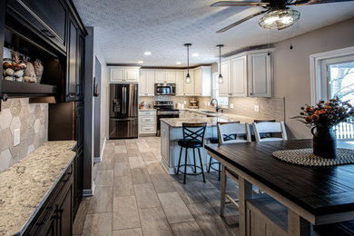 Eat-in kitchen - mid-sized transitional u-shaped vinyl floor and gray floor eat-in kitchen idea in Cleveland with an undermount sink, raised-panel cabinets, white cabinets, quartz countertops, gray backsplash, porcelain backsplash, black appliances, a peninsula and beige countertops