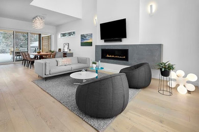 Example of a large minimalist formal and open concept light wood floor and brown floor living room design in Calgary with white walls, a ribbon fireplace, a stone fireplace and a wall-mounted tv