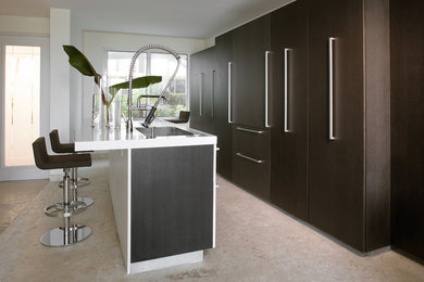 This is an example of a contemporary eat-in kitchen in Miami with an undermount sink, flat-panel cabinets, dark wood cabinets, solid surface benchtops and panelled appliances.