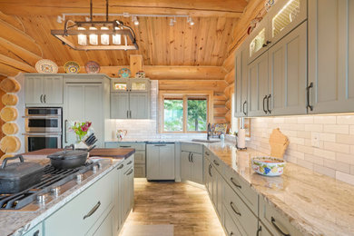 Example of a large mountain style l-shaped vaulted ceiling open concept kitchen design in Denver with an undermount sink, recessed-panel cabinets, green cabinets, granite countertops, white backsplash, subway tile backsplash, stainless steel appliances, an island and gray countertops