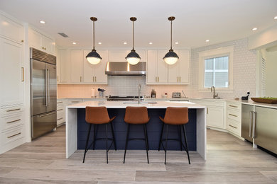 Photo of a large beach style u-shaped eat-in kitchen in Tampa with a single-bowl sink, beaded inset cabinets, white cabinets, quartz benchtops, white splashback, ceramic splashback, stainless steel appliances, porcelain floors, with island, beige floor and white benchtop.
