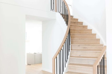 Photo of a large transitional wood spiral staircase in Calgary with wood risers and mixed railing.