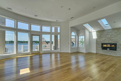 Game room - huge coastal open concept light wood floor and brown floor game room idea in Newark with white walls, a standard fireplace, a stone fireplace and a wall-mounted tv