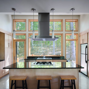 Создайте стильный интерьер: маленькая п-образная кухня-гостиная в современном стиле с накладной раковиной, стеклянными фасадами, светлыми деревянными фасадами, столешницей из гранита, черным фартуком, фартуком из каменной плиты, техникой из нержавеющей стали, полом из травертина и островом - последний тренд