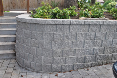 This is an example of a medium sized contemporary front driveway garden in Seattle with a retaining wall and concrete paving.