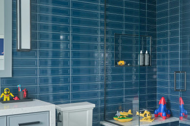 Bathroom - transitional kids' blue tile gray floor bathroom idea in Other with flat-panel cabinets, blue cabinets, a two-piece toilet, a hinged shower door, white countertops, a niche and a built-in vanity