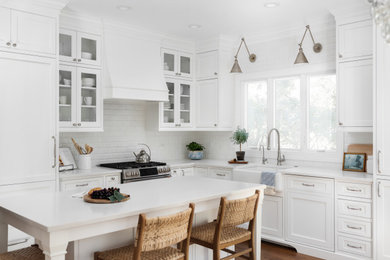 Mid-sized transitional l-shaped medium tone wood floor and brown floor eat-in kitchen photo in Chicago with a farmhouse sink, beaded inset cabinets, white cabinets, quartz countertops, white backsplash, ceramic backsplash, paneled appliances, an island and white countertops