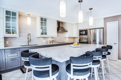 Inspiration for a mid-sized transitional l-shaped ceramic tile enclosed kitchen remodel in Toronto with an undermount sink, raised-panel cabinets, white cabinets, quartz countertops, beige backsplash, porcelain backsplash, stainless steel appliances and an island