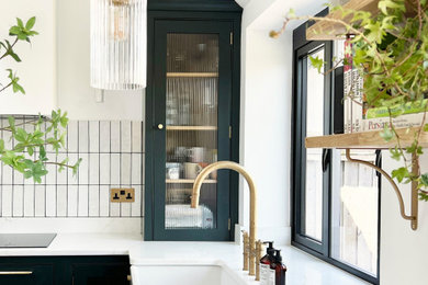 Inspiration for an eclectic u-shaped kitchen in Other with a belfast sink, shaker cabinets, green cabinets, quartz worktops, white splashback, porcelain splashback, stainless steel appliances and white worktops.