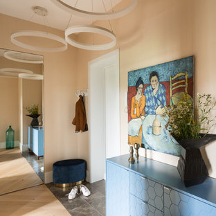 Inspiration pour une petite entrée bohème avec un vestiaire, un mur beige, un sol en carrelage de porcelaine, une porte simple, une porte blanche et un sol gris.