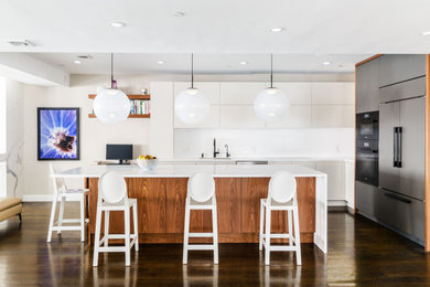 Inspiration for a large modern u-shaped vaulted ceiling eat-in kitchen remodel in New York with an integrated sink, flat-panel cabinets, white cabinets, quartz countertops, white backsplash, quartz backsplash, black appliances, an island and white countertops