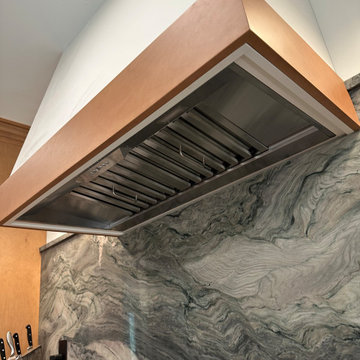 Custom white-and-wood vent hood over a dramatic, veined stone wall