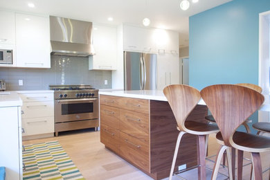 Mid-sized trendy l-shaped medium tone wood floor enclosed kitchen photo in San Francisco with an undermount sink, flat-panel cabinets, white cabinets, quartz countertops, gray backsplash, glass tile backsplash, stainless steel appliances and an island