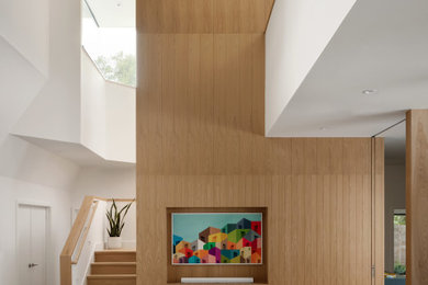 Example of a large 1960s loft-style light wood floor, beige floor and vaulted ceiling living room design in Austin with beige walls, no fireplace and a wall-mounted tv