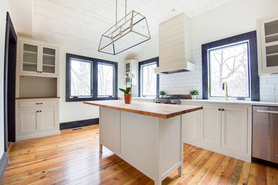 Photo of a mid-sized transitional u-shaped separate kitchen in Charleston with a double-bowl sink, shaker cabinets, white cabinets, marble benchtops, white splashback, subway tile splashback, stainless steel appliances, medium hardwood floors, with island and beige floor.