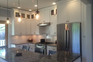 Eat-in kitchen - large transitional u-shaped medium tone wood floor eat-in kitchen idea in Portland with an undermount sink, recessed-panel cabinets, white cabinets, granite countertops, white backsplash, subway tile backsplash, stainless steel appliances and an island