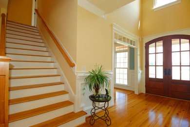 Photo of a large contemporary hallway in Boston with yellow walls and light hardwood floors.