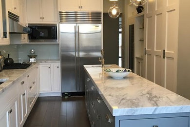Example of a large transitional u-shaped dark wood floor and brown floor enclosed kitchen design in Chicago with an undermount sink, shaker cabinets, white cabinets, marble countertops, stainless steel appliances and an island
