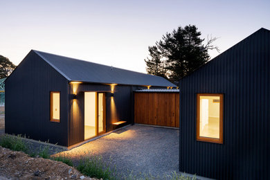 Inspiration for a large contemporary one-storey black house exterior with metal siding, a gable roof and a metal roof.