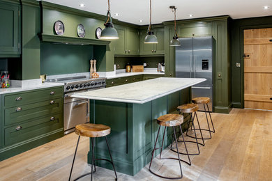 Photo of a country l-shaped separate kitchen in Other with shaker cabinets, green cabinets, stainless steel appliances, light hardwood floors, with island and beige floor.