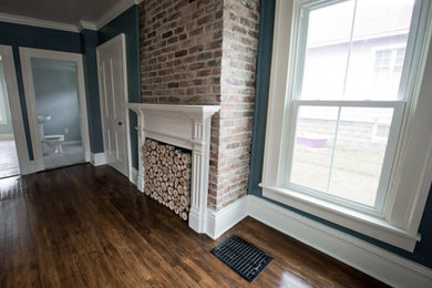 Example of a large classic master medium tone wood floor and brown floor bedroom design in Other with blue walls, a standard fireplace and a wood fireplace surround