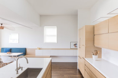 This is an example of a mid-sized contemporary single-wall eat-in kitchen in San Francisco with an undermount sink, flat-panel cabinets, dark wood cabinets, quartz benchtops, white splashback, panelled appliances, dark hardwood floors, with island and white benchtop.