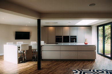 Design ideas for a large modern open plan kitchen in Cheshire with white cabinets, quartz worktops, black appliances, an island and white worktops.