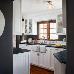 Diseño de cocina en U, marinera, de tamaño medio, cerrada, sin isla, con fregadero sobremueble, armarios con paneles empotrados, puertas de armario blancas, encimera de esteatita, salpicadero blanco, salpicadero de azulejos tipo metro, electrodomésticos de acero inoxidable y suelo de madera oscura