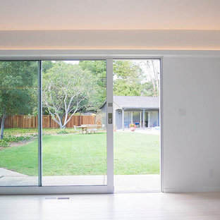Foto di un grande soggiorno moderno aperto con sala formale, pareti bianche, parquet chiaro, camino lineare Ribbon, cornice del camino in pietra e TV nascosta