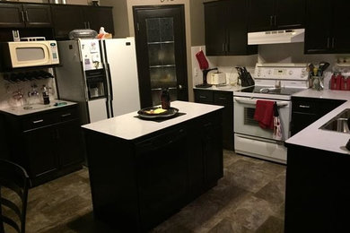 Mid-sized trendy u-shaped ceramic tile eat-in kitchen photo in Louisville with a double-bowl sink, recessed-panel cabinets, black cabinets, solid surface countertops, white backsplash, white appliances and an island
