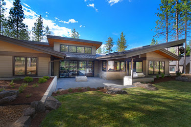Large rustic beige one-story concrete fiberboard house exterior idea in Other with a shed roof and a metal roof
