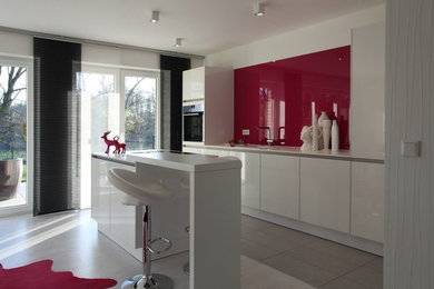 Offene, Einzeilige, Geräumige Moderne Küche mit Waschbecken, Küchenrückwand in Rosa, Glasrückwand, schwarzen Elektrogeräten, Kücheninsel, grauem Boden und weißer Arbeitsplatte in Sonstige