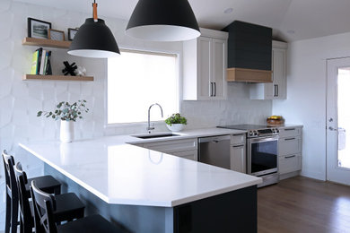 Eat-in kitchen - mid-sized modern l-shaped laminate floor and brown floor eat-in kitchen idea in Other with an undermount sink, shaker cabinets, white cabinets, solid surface countertops, white backsplash, stainless steel appliances, a peninsula and white countertops